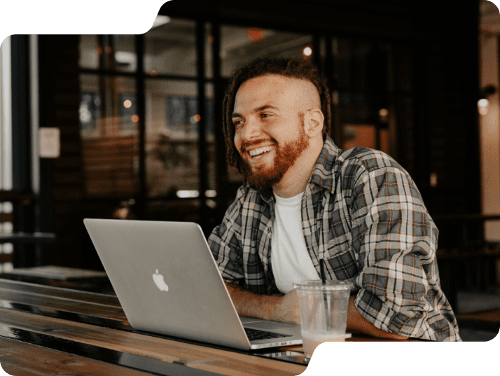 Man smiling at table on laptop.