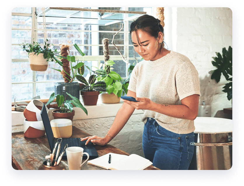 Woman on laptop with plants surrounding her.