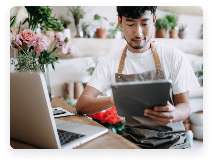 Man at cafe on tablet with laptop in front of him.