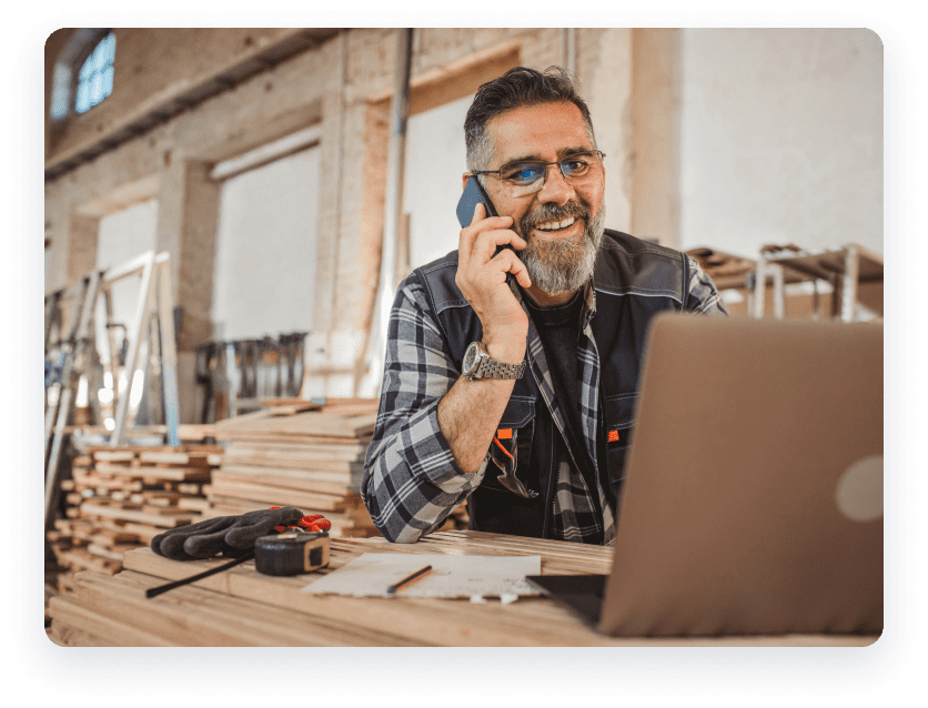 Man in workshop on phone and laptop.