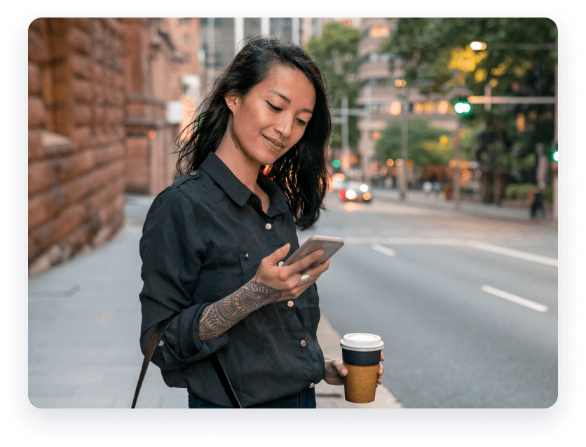 Woman on the street holding phone and coffee