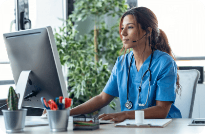 Woman at clinic with headset on using a computer.