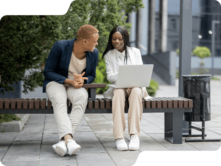 Colleagues sitting on a park bench on a laptop