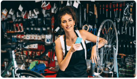 Woman holding phone at a bike shop.