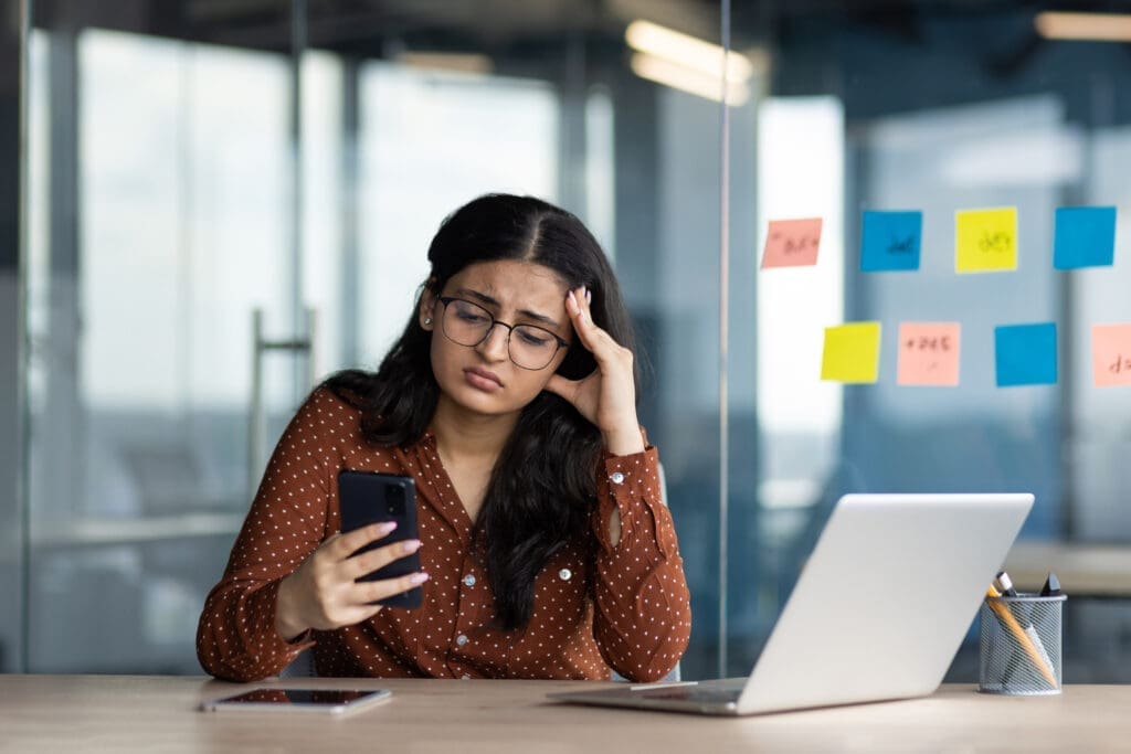 Frustrated businesswoman looking at her phone during a network outage, experiencing communication downtime