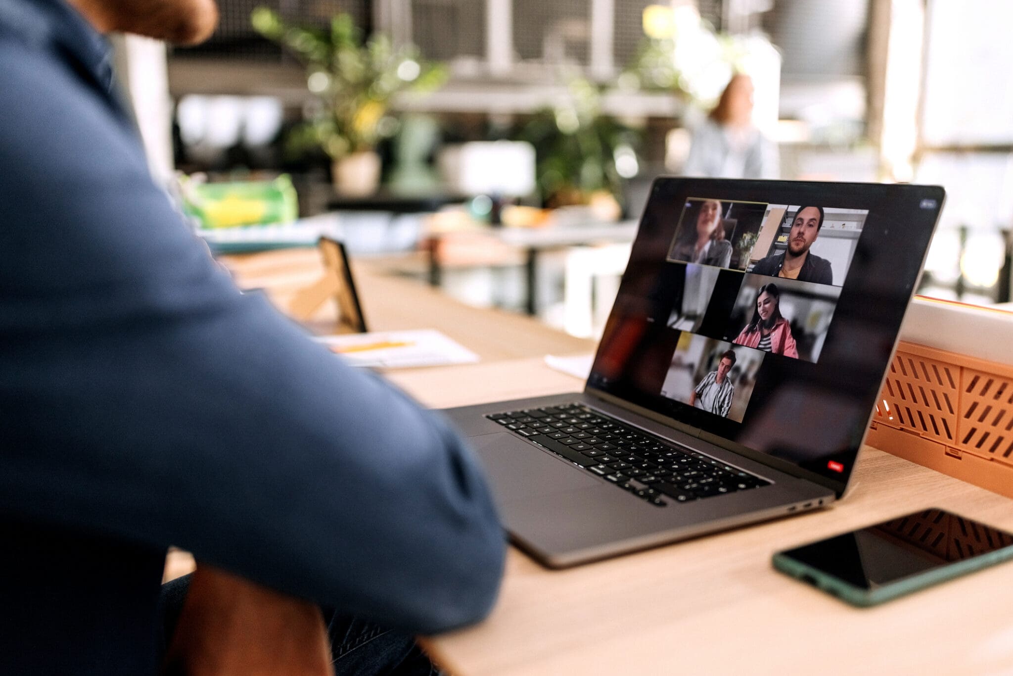 Remote worker using a laptop to attend a virtual team video meeting, representing modern VoIP and cloud-based communication.