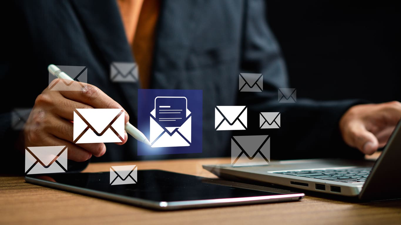 Close-up of a person using a tablet and laptop to securely send a document via eFax in a professional setting.
