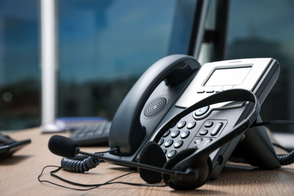 A close-up of a traditional desk phone with headset, symbolizing outdated communication methods compared to a modern VoiP system.