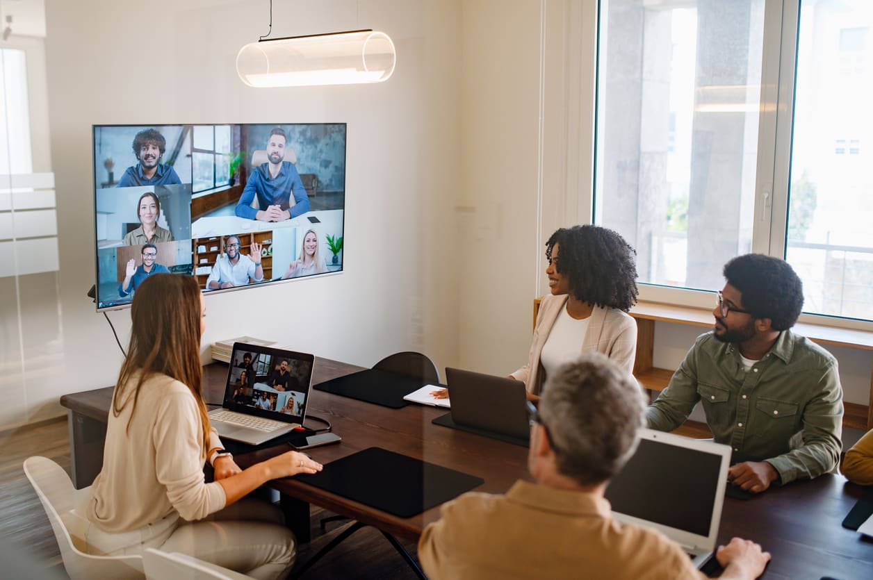 A hybrid team in an office participates in a video conference with remote colleagues, illustrating collaboration using U-Fax.