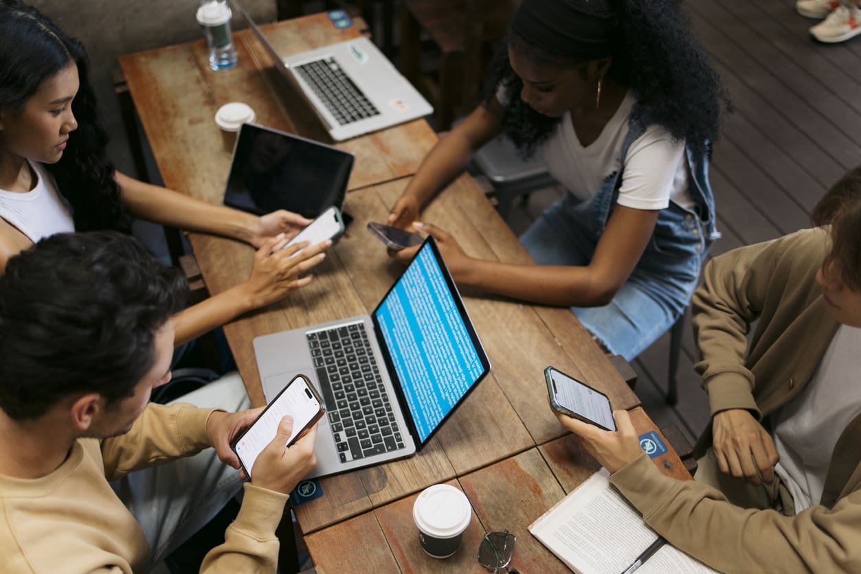A team collaborates around a desk in a modern office, using VoIP phone service and digital communication tools.
