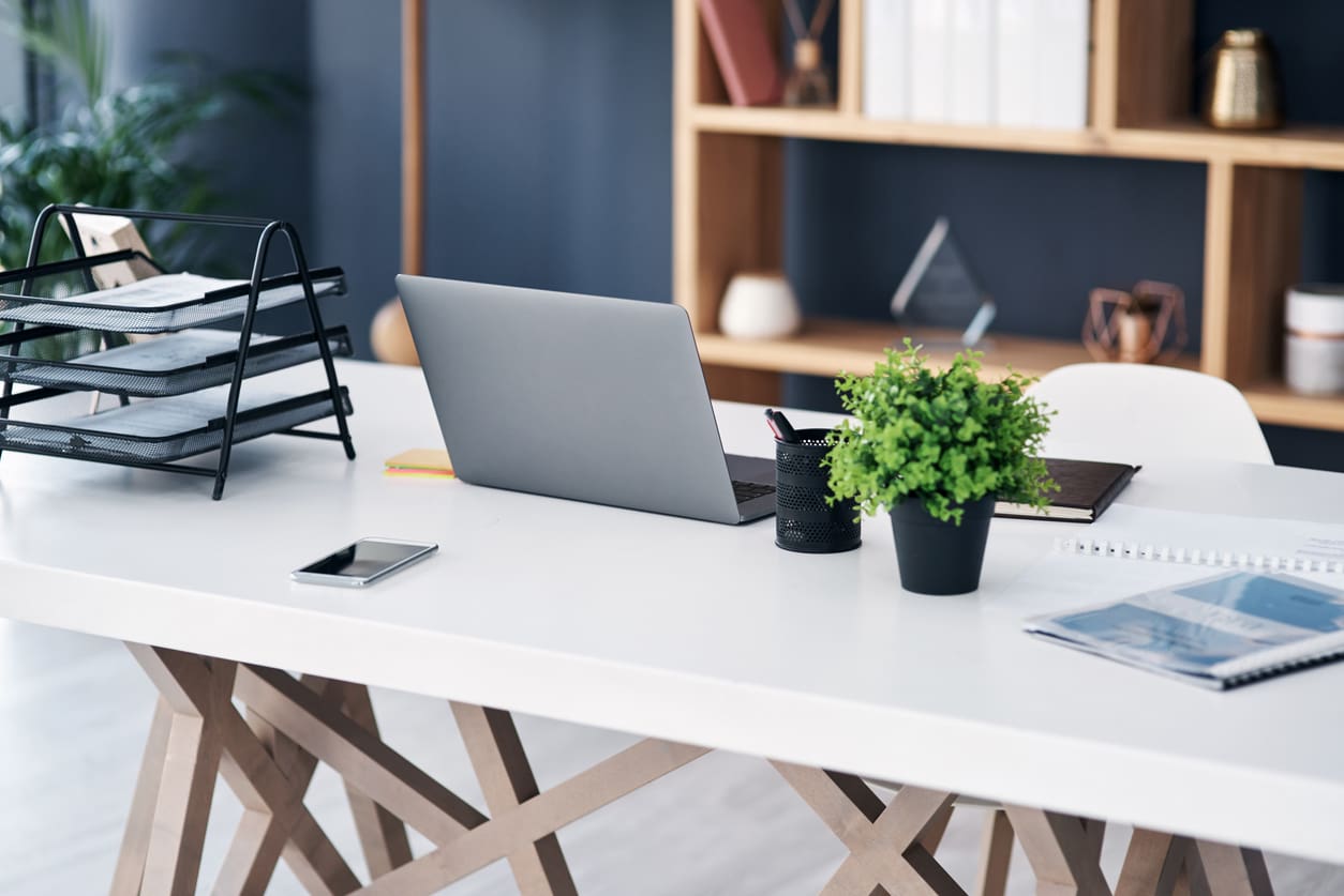 Neat office desk with laptop, phone and documents, displaying a clutter-free environment when using electronic faxing.