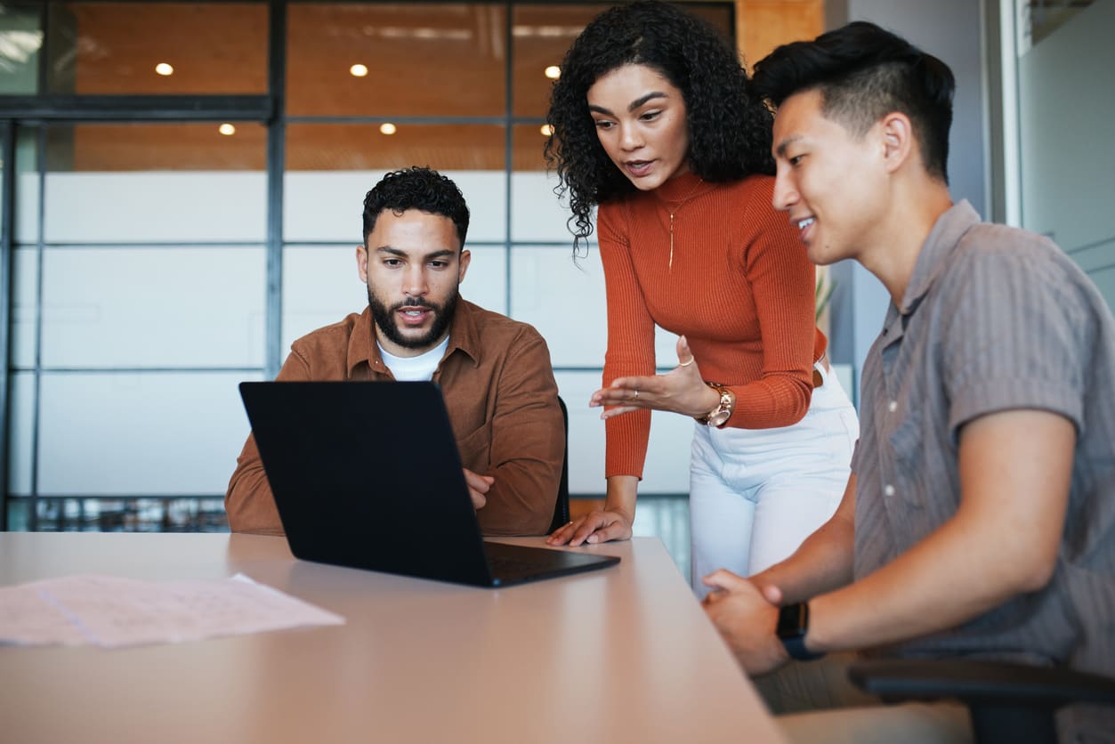 Small business team collaborating around a laptop in a modern office environment on VoIP phone system.